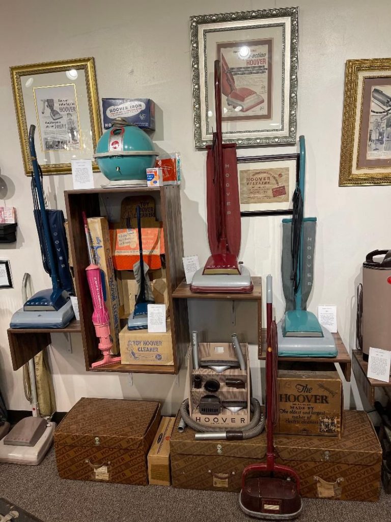 a group of Vintage Hoover 1950s Vacuums on shelves