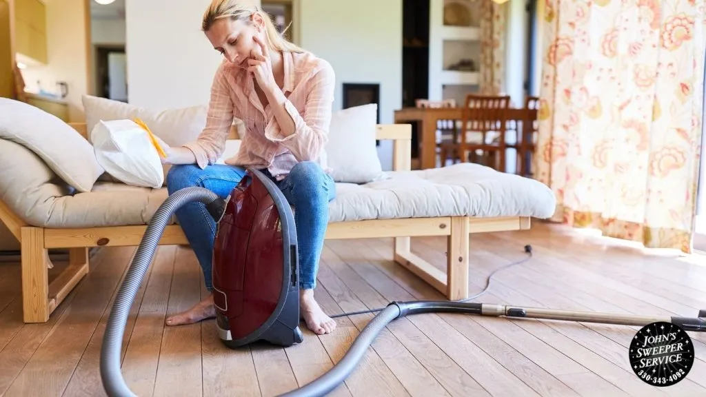 a person sitting on the floor with a vacuum cleaner